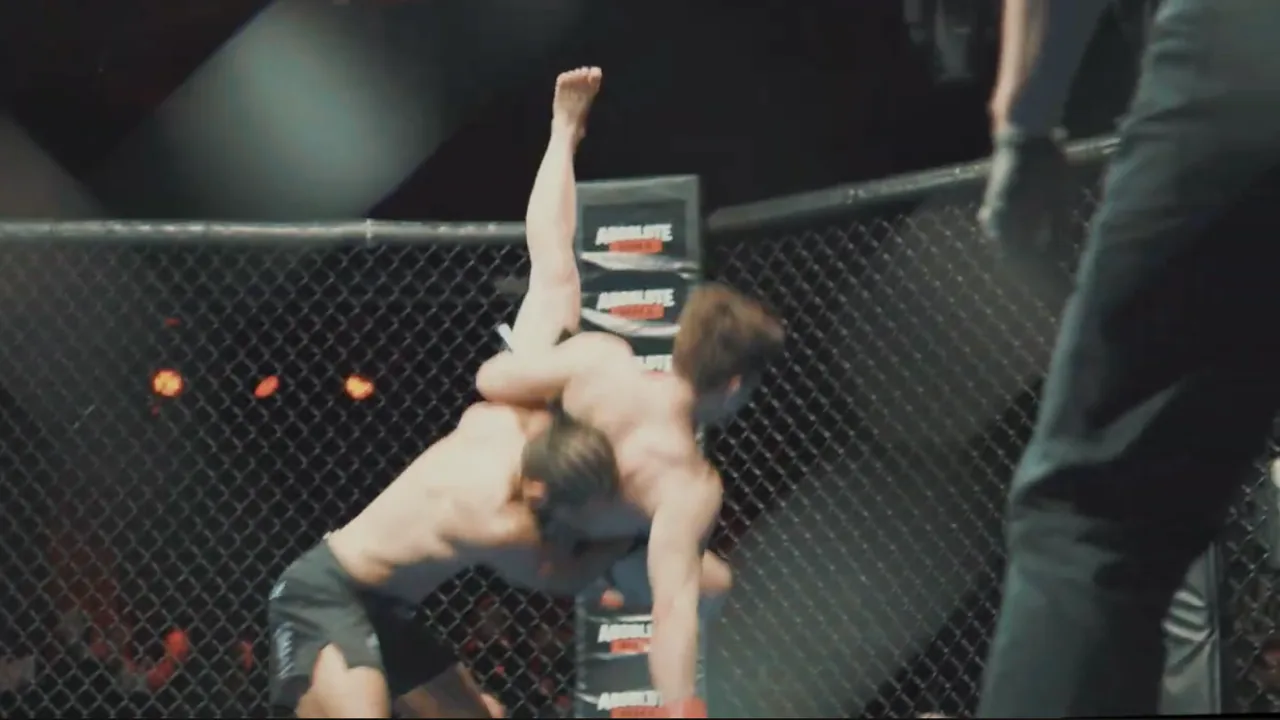 A fighter lifting his opponent for a slam against the cage fence